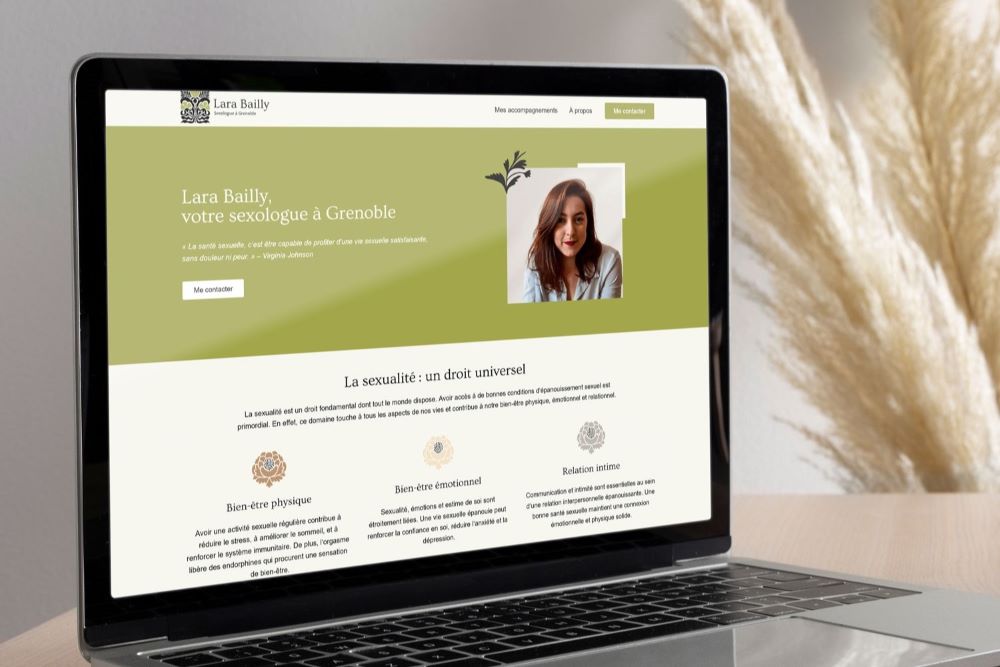 Ordinateur portable sur un bureau en bois présentant le site de Lara Bailly, sexothérapeute à Grenoble, avec un design floral et vert